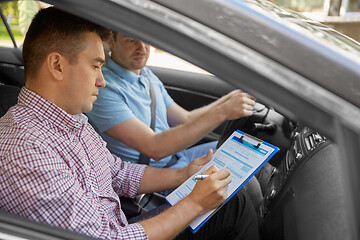 Image showing car driving instructor with clipboard and driver