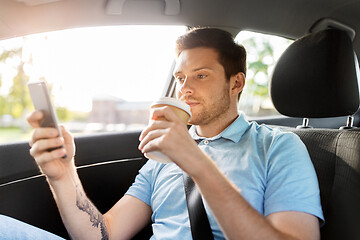 Image showing passenger drinking coffee using smartphone in car