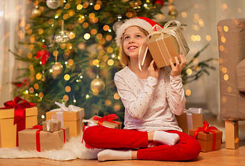 Image showing smiling girl in santa hat with christmas gift