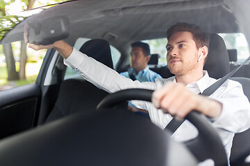 Image showing male driver with wireless earphones driving car