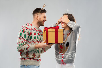 Image showing happy couple in christmas sweaters with gift box