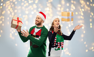 Image showing happy couple in ugly sweaters with christmas gift