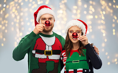 Image showing happy couple in christmas sweaters and santa hats