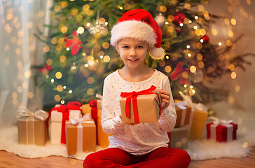 Image showing smiling girl in santa hat with christmas gift