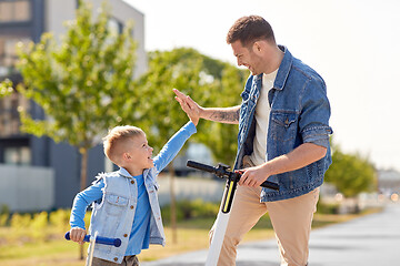 Image showing father and son with scooters making high five