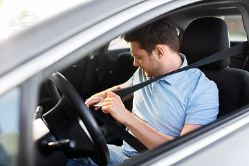 Image showing man or car driver fastening seat belt