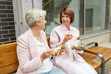 Image showing senior women eating takeaway food on city street