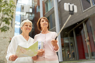 Image showing senior women with map and city guide taking selfie