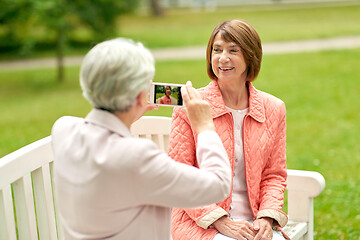 Image showing senior woman photographing her friend at park