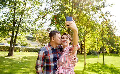 Image showing happy couple in park taking selfie by smartphone