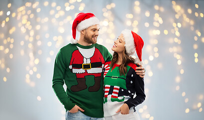 Image showing happy couple in christmas sweaters and santa hats