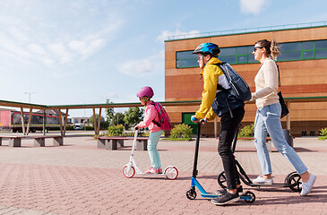 Image showing happy school children with mother riding scooters