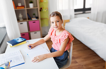 Image showing student girl with book writing to notebook at home