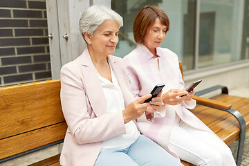 Image showing happy senior women with smartphones in city