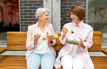 Image showing senior women eating takeaway food on city street