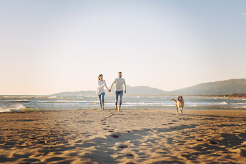 Image showing couple with dog having fun on beach on autmun day