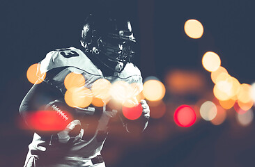 Image showing American football player holding ball while running on field