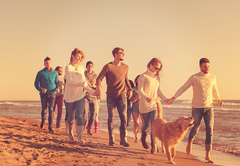 Image showing Group of friends running on beach during autumn day