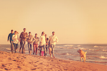 Image showing Group of friends running on beach during autumn day