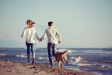 Image showing couple with dog having fun on beach on autmun day