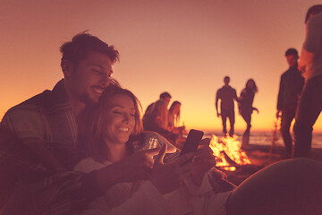 Image showing Couple enjoying bonfire with friends on beach