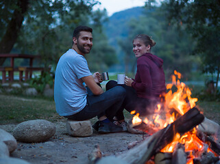 Image showing couple sitting around the campfire at evening