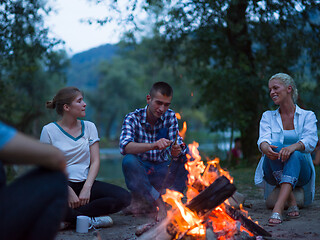 Image showing young friends relaxing around campfire