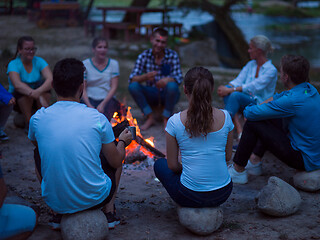 Image showing young friends relaxing around campfire