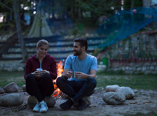 Image showing couple sitting around the campfire at evening