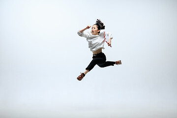 Image showing Woman working at office and jumping isolated on studio background