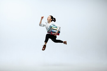 Image showing Woman working at office and jumping isolated on studio background