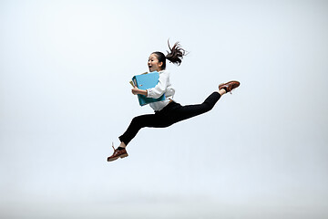 Image showing Woman working at office and jumping isolated on studio background