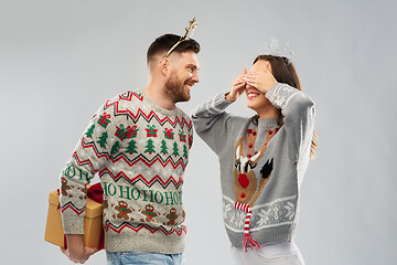 Image showing happy couple in christmas sweaters with gift box