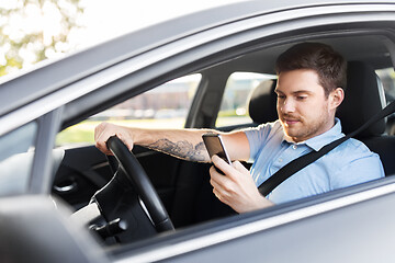 Image showing man driving car and using smartphone