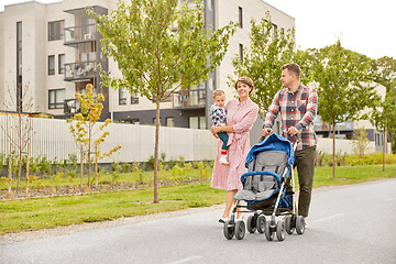 Image showing family with baby and stroller walking along city