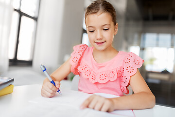 Image showing student girl with book writing to notebook at home