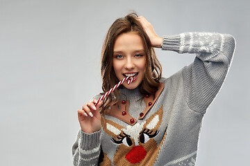 Image showing woman in christmas sweater eating candy cane