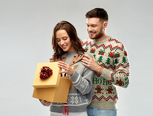 Image showing happy couple in christmas sweaters with gift box