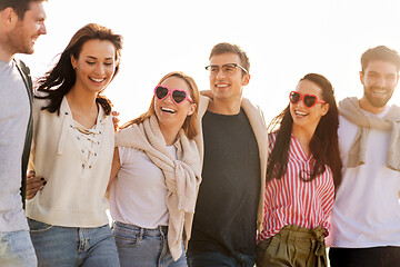 Image showing happy friends walking along summer beach