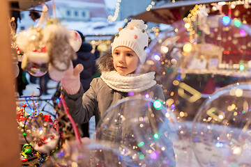 Image showing little girl choosing christmas balls at market