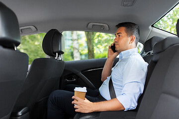 Image showing businessman with coffee calling on phone in car