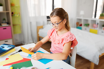 Image showing girl with color paper sitting at table at home