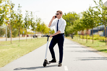 Image showing businessman with scooter calling on smartphone