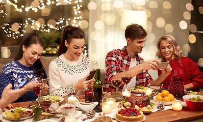 Image showing friends with smartphones having christmas dinner