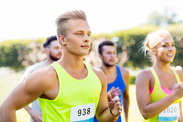 Image showing happy young sportsmen racing wit badge numbers