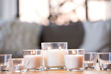 Image showing burning white fragrance candles on table at home