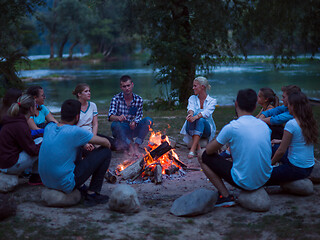 Image showing young friends relaxing around campfire