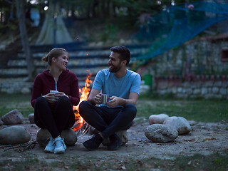 Image showing couple sitting around the campfire at evening