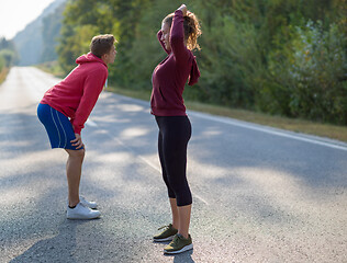 Image showing young couple warming up and stretching on a country road