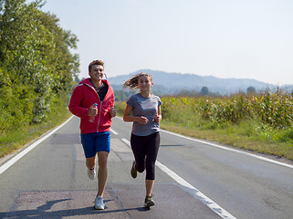 Image showing young couple jogging along a country road